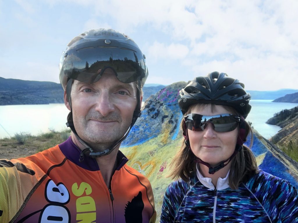 Joel and Linda Chamaschuk cycling in front of Painted Rock